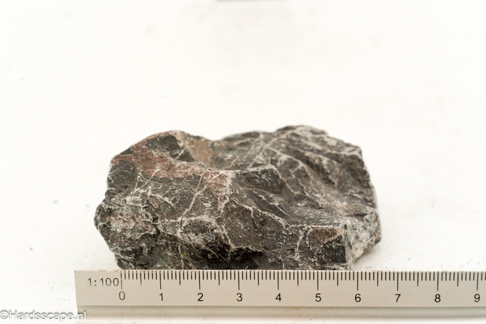 Kleine Dark Hell Stone S083 van Hardscape.nl met donkere, ruwe textuur en natuurlijke uitstraling op een grijze achtergrond