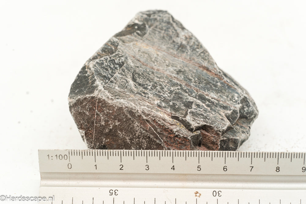 Kleine Dark Hell Stone S094 van Hardscape.nl met een donkergrijze, ruwe natuursteen structuur op een tuinpaadje