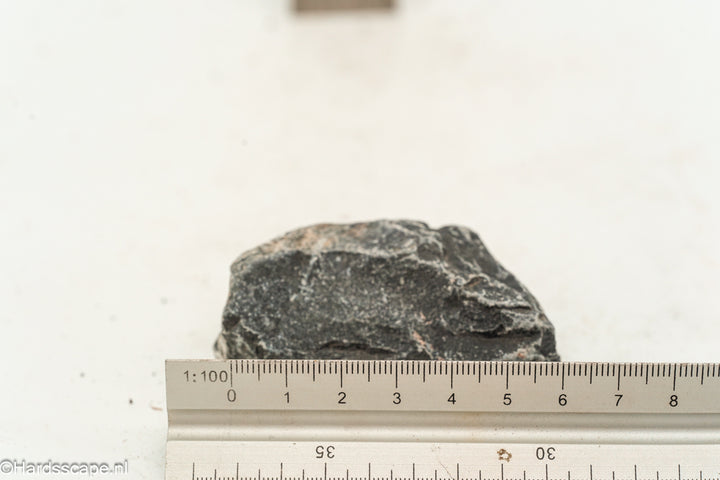 Kleine Dark Hell Stone S115 van Hardscape.nl, donkergekleurd natuursteen met ruwe textuur en sierlijke vorm voor tuinverharding